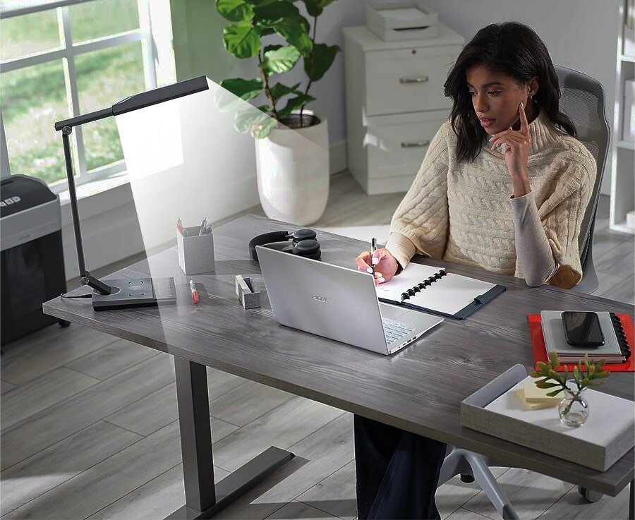 Lady working at desk with LED desk lamp illuminating desk.