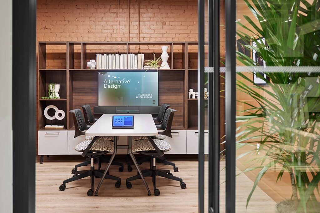Stylish enclosed meeting room with warm natural tones, wood finishes, and a lush tropical plant.