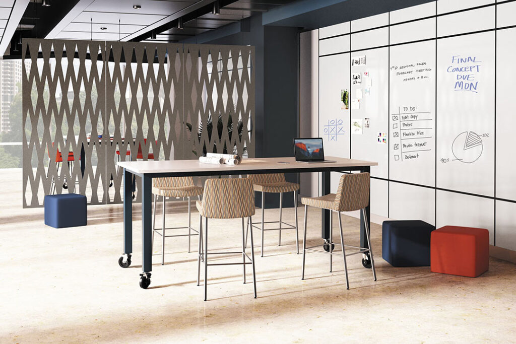 Office breakout space featuring an acoustic wall, movable desk, and high-top chairs.