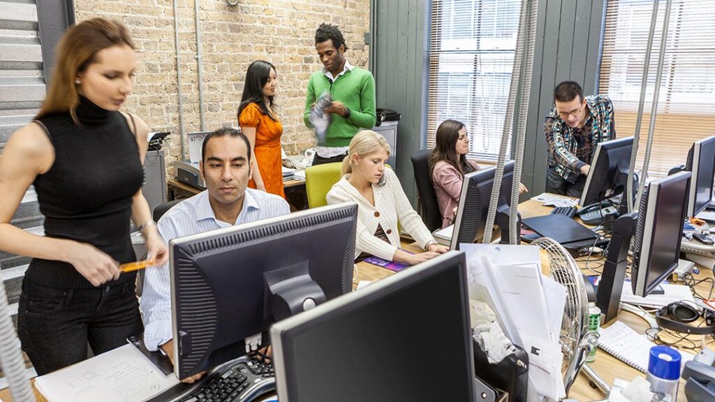 Crowded open office filled with multiple employees working at their desks.